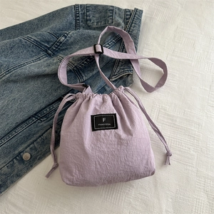 Detail shot of purple drawstring bucket bag with branded label and adjustable strap