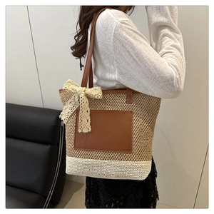 Detail of woven straw tote bag featuring a lace bow and brown leather shoulder straps