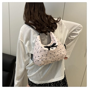 Sac à bandoulière matelassé rose clair avec nœud et pendentif cœur sur modèle