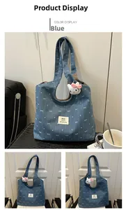 Detail of blue denim tote bag with butterfly patterns and plush cat pendant accessory