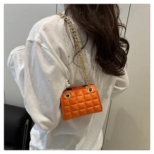 Détail du sac bandoulière en cuir matelassé orange avec chaîne en métal doré