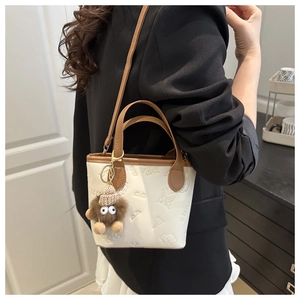 Mini white bucket bag with embossed patterns and plush charm on a female model