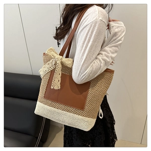 Detail of hand-woven straw tote with white panels, lace bow, and leather straps
