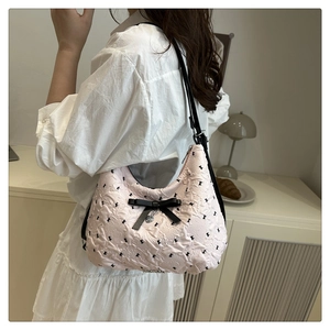 Détail du sac à bandoulière rose avec motif à nœuds et pendentif en forme de cœur
