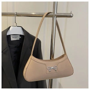 Detailed close-up of a chic beige leather baguette bag with a silver bow buckle and zip