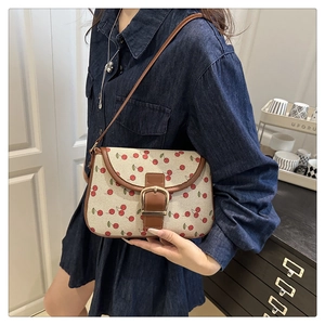 Gros plan d'un sac bandoulière en toile à imprimé cerise et bandoulière en cuir marron
