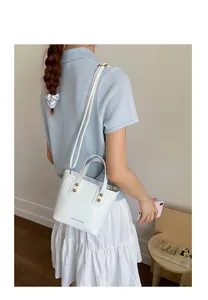 Chic white mini bucket bag with metal studs and detachable shoulder strap on model