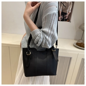 Chic black litchi grain tote bag with gold hardware shown on model in home setting