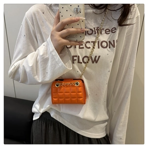 Gros plan sur le mini sac matelassé orange vif avec détails de bandoulière dorée