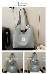 Detail of light blue canvas tote bag with white bow pattern and plush kitten charm