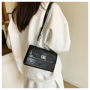 Detail of black crocodile texture shoulder bag with silver clasp and chain strap