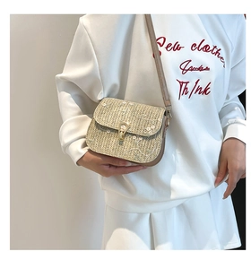 Detail of straw saddle bag with white flower embroidery and brown leather strap