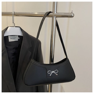 Detail of black underarm bag with silver bow ornament hanging on a metal hanger