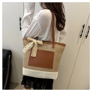 Close-up of handwoven straw tote bag with lace bow and leather pocket on shoulder