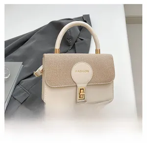 Detail of beige crossbody bag with woven texture flap and golden buckle on grey blazer