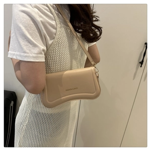 Detail of beige faux leather shoulder bag with FASHION & BAGS text and curved bottom