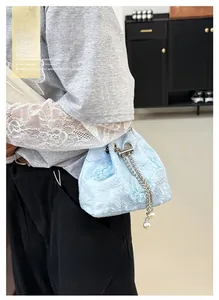 Detail of light blue lace bucket bag with 3D butterfly appliques and pearl chain drawstring