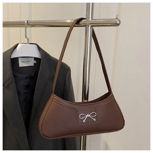 Detail view of a brown matte leather crescent bag featuring a silver metal bow buckle