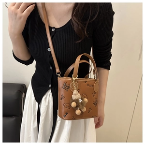 Detail of brown leather bucket bag with cartoon prints and a cute lion plush pendant