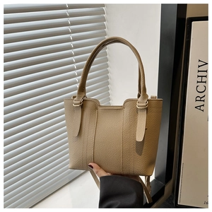 Detailed view of khaki lychee grain leather handbag with gold-tone metal hardware