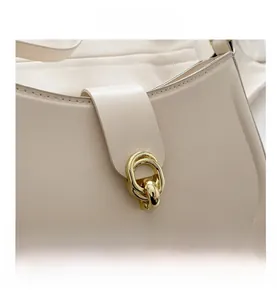Close-up of cream leather handbag featuring a stylish gold interlocking metal buckle