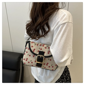Detail of cherry print canvas shoulder bag with black leather trim and gold buckle accent