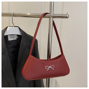 Detail of silver metallic bow buckle on deep red crescent-shaped shoulder bag