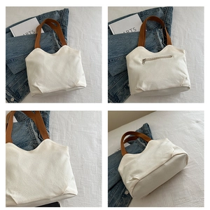 Detail of off-white canvas tote bag featuring back zipper pocket and brown strap