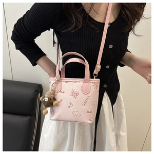 Pink bucket bag with cute dog prints and plush bear charm shown on a model