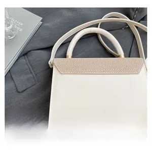 Detail of a minimalist cream shoulder bag featuring brown woven texture and gold hardware