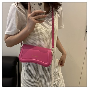 Detail of a bright pink wave-base crossbody bag with fine leather texture and flap design