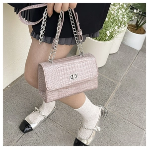 Gros plan du sac rose texture crocodile avec chaîne argentée et fermoir pivotant