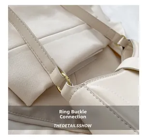 Detailed shot of light gold ring hardware and stitching on a beige leather shoulder bag