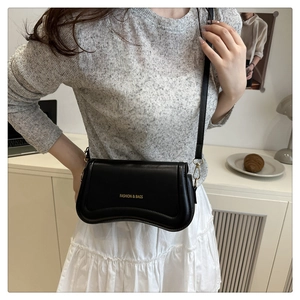 Detail of black crossbody bag with wave curve base and gold fashion lettering