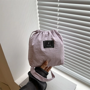 Minimalist lavender nylon drawstring bucket bag with black square F logo held by hand