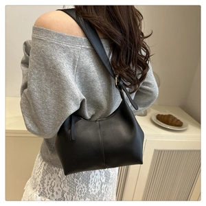 Close-up of a black leather hobo shoulder bag with adjustable strap worn by a model