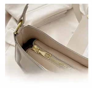 Detailed close-up of smooth gold metal zipper on beige leather bag with neat stitching