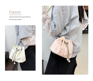 Detail of floral butterfly embroidery on lace satin drawstring bucket bag with pearl charms