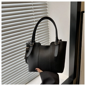 Detail of black lychee grain leather handbag with gold metal hardware and side buckle