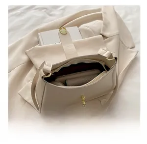 Top view of open beige leather shoulder bag showing spacious interior and gold hardware