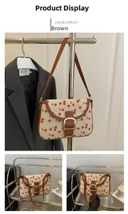 Détails du sac bandoulière en toile avec motif cerise et lanière en cuir marron