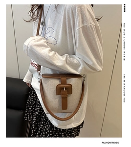 Détail du sac seau vintage en toile beige avec garniture en cuir marron et boucle en métal