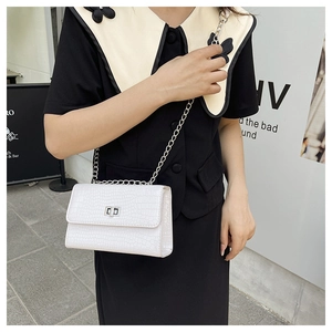 Détail d'un sac blanc à motif crocodile avec chaîne argentée et fermoir pivotant en métal