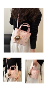 Detail of light pink crossbody bucket bag with butterfly prints and plush monster charm