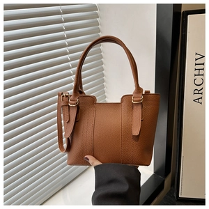 Detailed view of dark brown pebbled leather texture and metal buckle on bucket bag