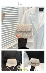 Detail of white woven straw saddle bag featuring floral embroidery and U-shaped clasp