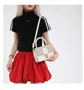 Détail du sac à main crème chic avec rabat tissé et bandoulière amovible porté avec tenue décontractée