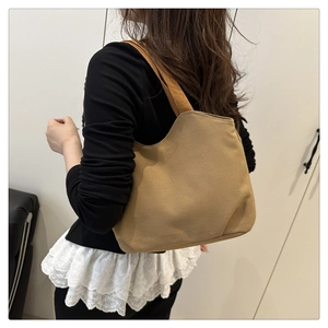 Detail of brown canvas tote bag with unique wavy edge and wide shoulder strap style