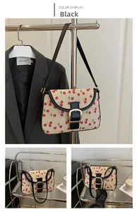 Détail du sac à bandoulière beige avec imprimé cerise et boucle en métal doré