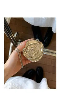 Detailed macro of golden rose acrylic evening bag with metallic snake chain and mirror finish